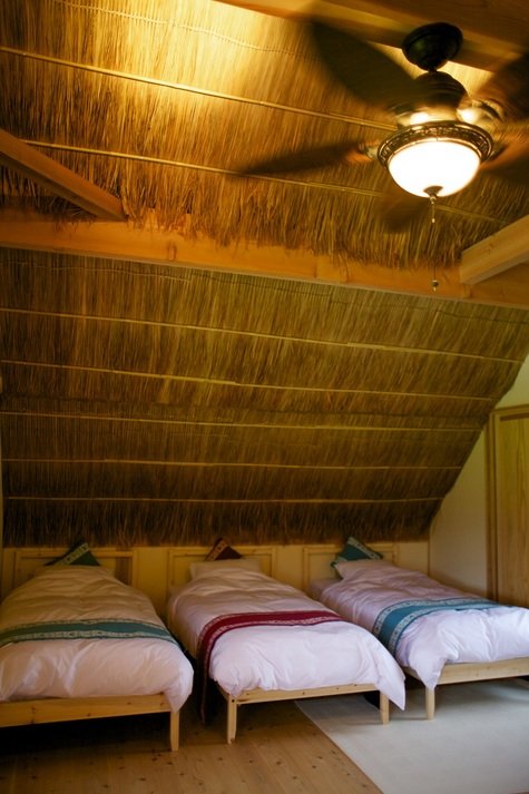 茅葺き屋根の下に並ぶベッドルーム